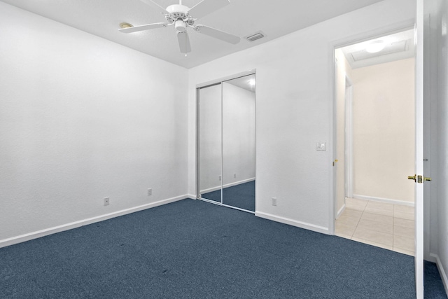 unfurnished bedroom featuring dark colored carpet, ceiling fan, and a closet