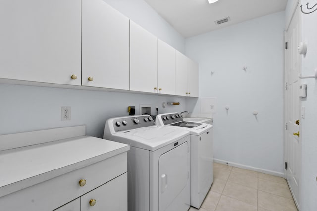 washroom featuring cabinets, light tile patterned floors, and washer and dryer