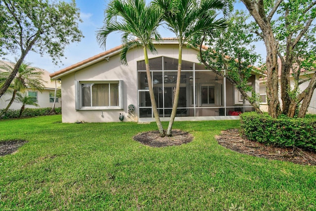 back of house featuring a sunroom and a lawn