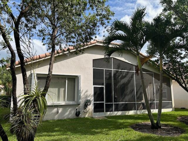 view of property exterior with a garage, a yard, a tile roof, and stucco siding