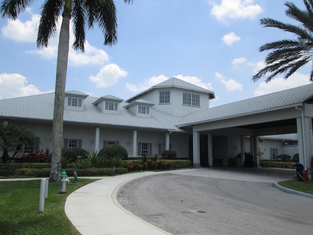 view of front facade featuring curved driveway, a tiled roof, and stucco siding