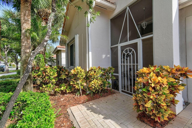 entrance to property with a wall unit AC and stucco siding