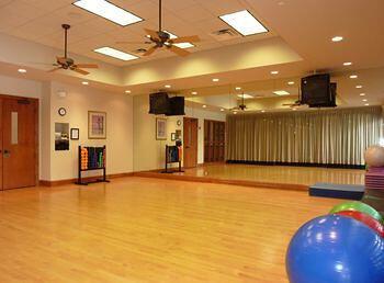 workout room with ceiling fan, a raised ceiling, and light hardwood / wood-style flooring