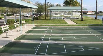 view of property's community featuring a water view, shuffleboard, and a yard