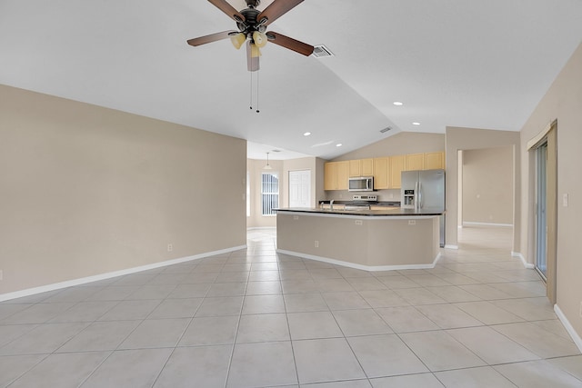 kitchen featuring stainless steel appliances, light brown cabinets, light tile patterned floors, lofted ceiling, and an island with sink