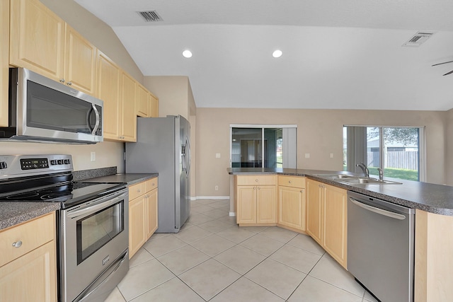 kitchen with sink, light tile patterned flooring, vaulted ceiling, and appliances with stainless steel finishes