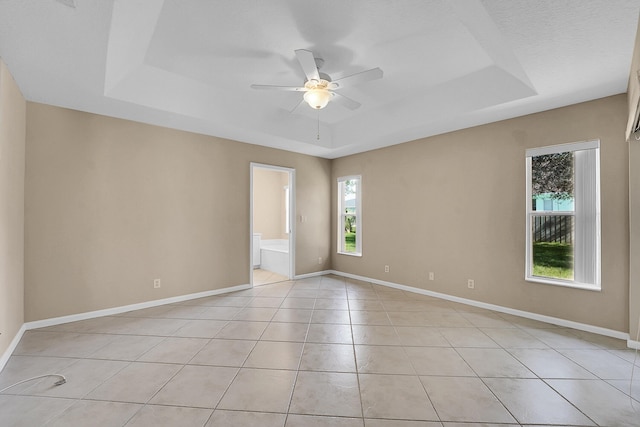 empty room featuring light tile patterned floors, a textured ceiling, a raised ceiling, and ceiling fan