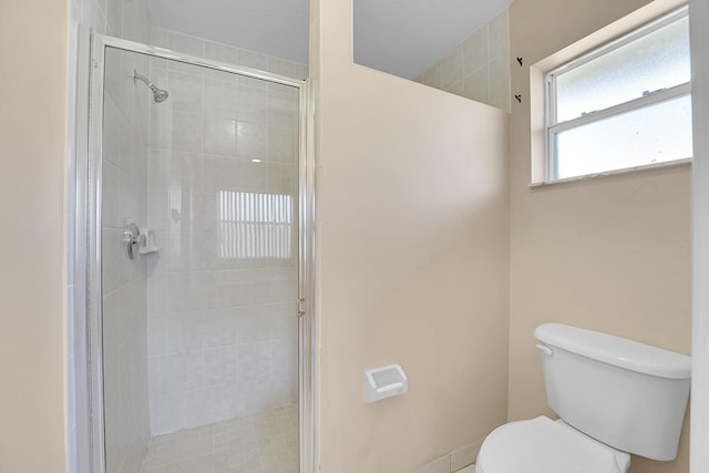 bathroom featuring toilet and a shower with shower door