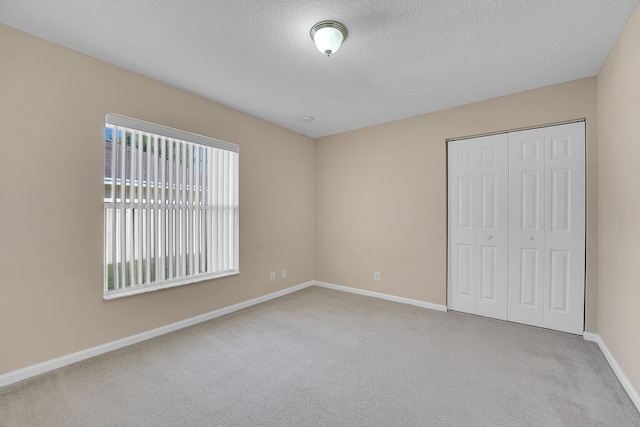 unfurnished bedroom featuring a closet, light colored carpet, and a textured ceiling