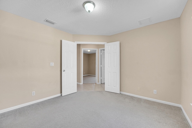 unfurnished room with a textured ceiling and light carpet