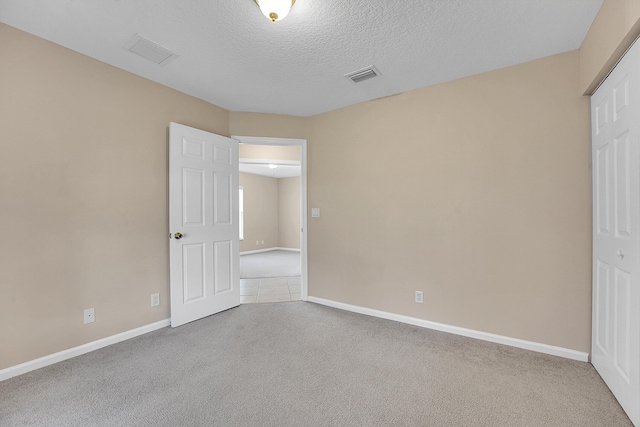 unfurnished bedroom featuring carpet, a textured ceiling, and a closet