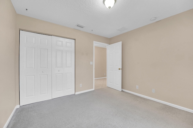 unfurnished bedroom featuring a closet, light colored carpet, and a textured ceiling