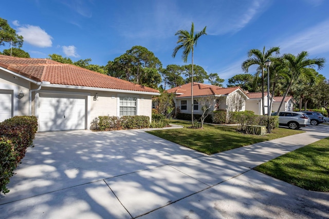 view of front of house featuring an attached garage, a tile roof, driveway, stucco siding, and a front lawn