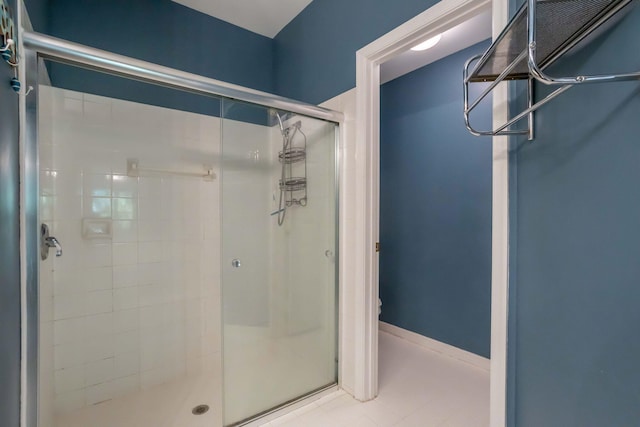 full bath with tile patterned flooring, a shower stall, and baseboards