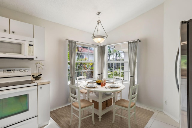 kitchen with white cabinetry, lofted ceiling, decorative light fixtures, white appliances, and light tile patterned floors