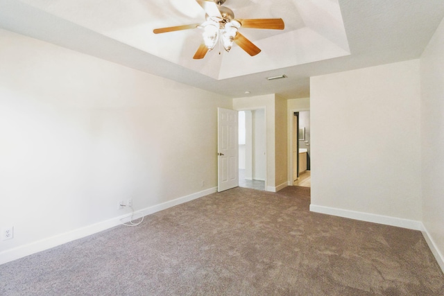 carpeted empty room with ceiling fan and a tray ceiling