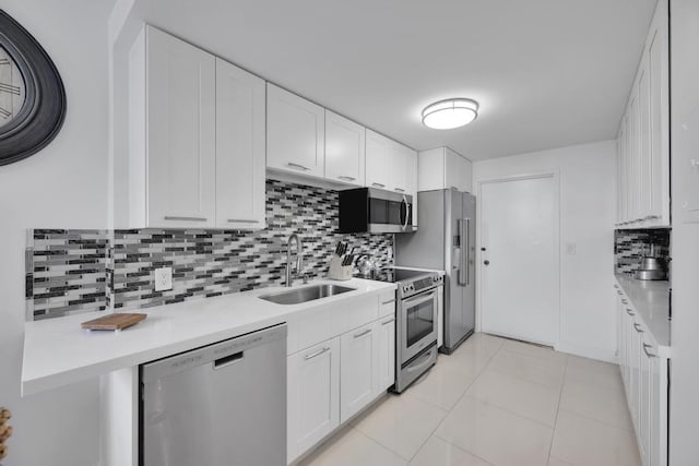 kitchen featuring sink, stainless steel appliances, white cabinets, backsplash, and light tile patterned flooring