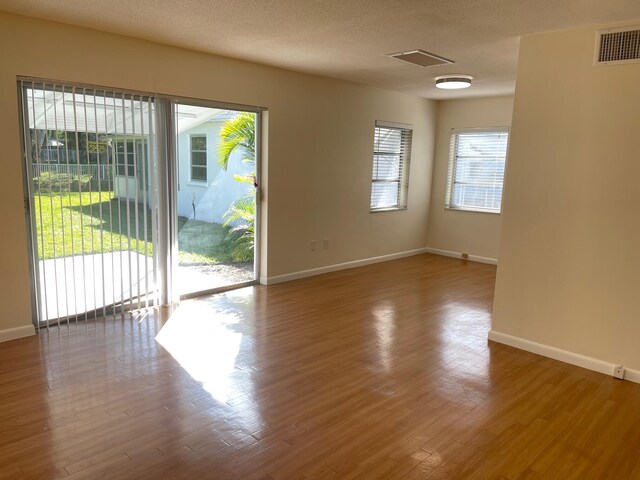 unfurnished room featuring hardwood / wood-style flooring and a textured ceiling