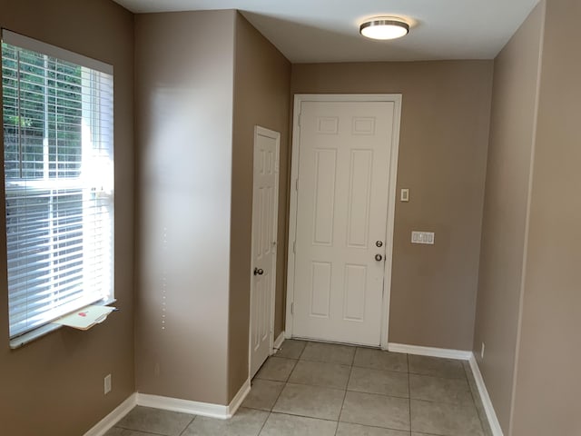 doorway to outside featuring light tile patterned floors, baseboards, and a wealth of natural light