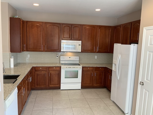 kitchen with white appliances, light tile patterned floors, backsplash, light stone countertops, and a sink