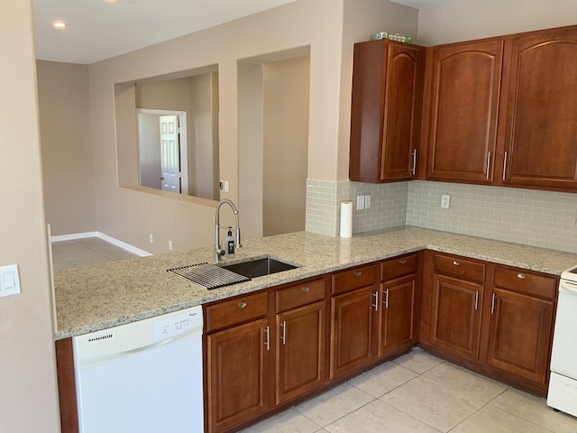 kitchen with decorative backsplash, dishwasher, a sink, and light stone countertops