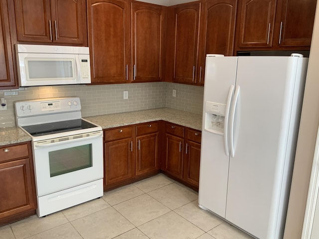 kitchen featuring tasteful backsplash, white appliances, light tile patterned flooring, and light stone countertops