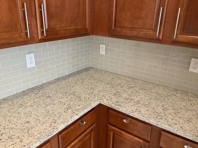 kitchen with light stone counters, brown cabinets, and decorative backsplash