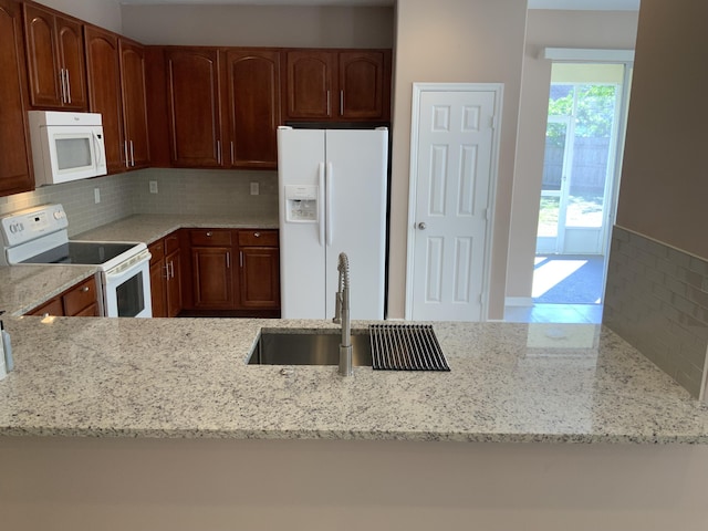 kitchen with white appliances, a sink, light stone counters, and tasteful backsplash