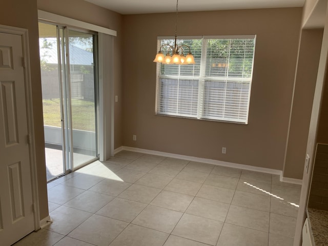 spare room featuring baseboards, plenty of natural light, light tile patterned flooring, and an inviting chandelier