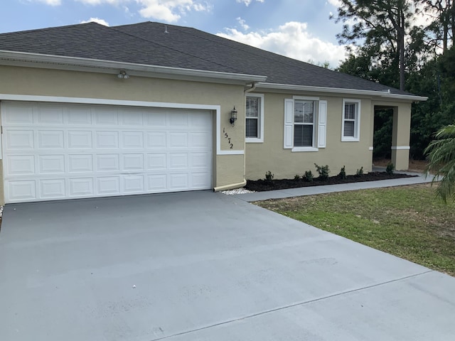 ranch-style house with roof with shingles, stucco siding, concrete driveway, an attached garage, and a front yard