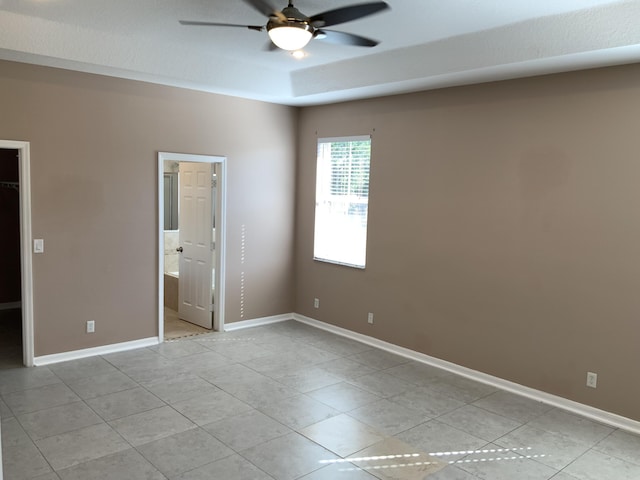 unfurnished bedroom featuring light tile patterned flooring, a spacious closet, baseboards, and ensuite bathroom