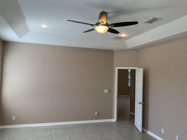 unfurnished room with light tile patterned floors, a tray ceiling, visible vents, and baseboards