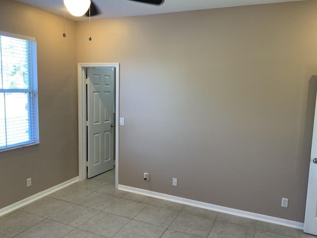 spare room with a ceiling fan, baseboards, and light tile patterned floors