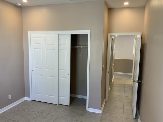 unfurnished bedroom with a closet, light tile patterned flooring, visible vents, and baseboards