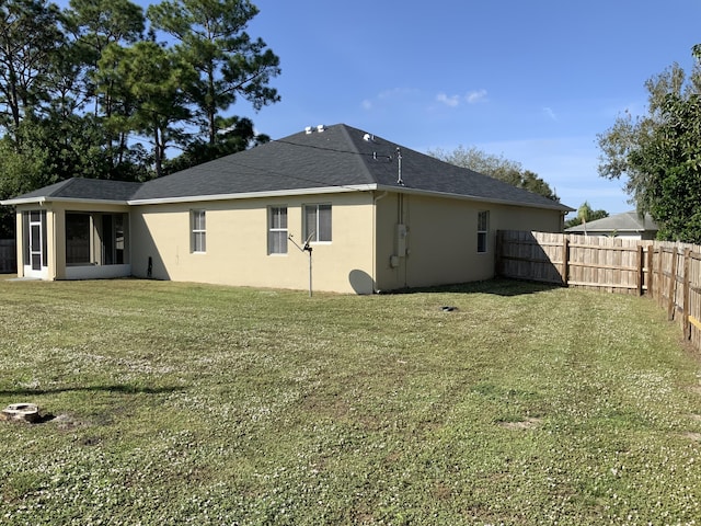 back of property featuring stucco siding, fence, and a yard