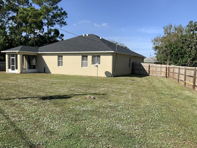 back of property with a yard, a fenced backyard, and stucco siding