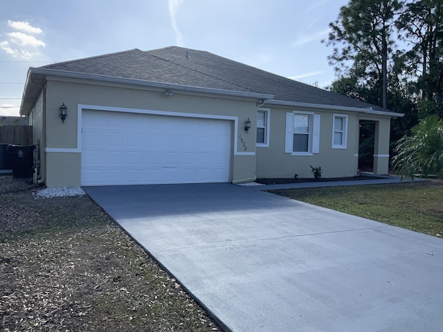 ranch-style home with a shingled roof, concrete driveway, a garage, and stucco siding