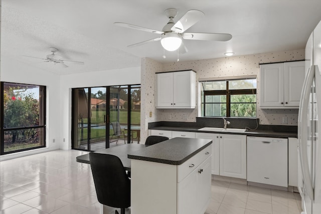 kitchen featuring a wealth of natural light, white cabinetry, sink, white appliances, and a kitchen island