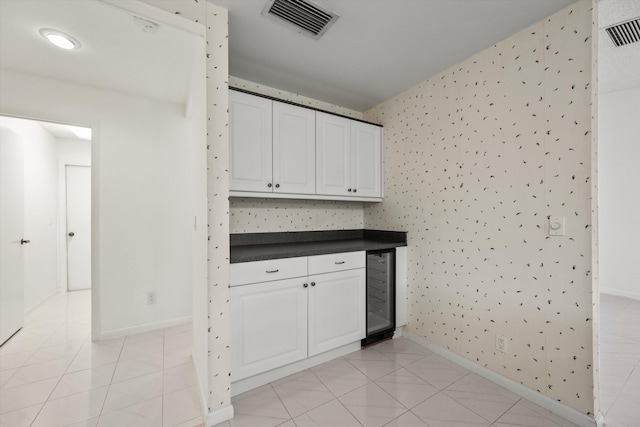 kitchen with wine cooler, white cabinetry, and light tile patterned floors