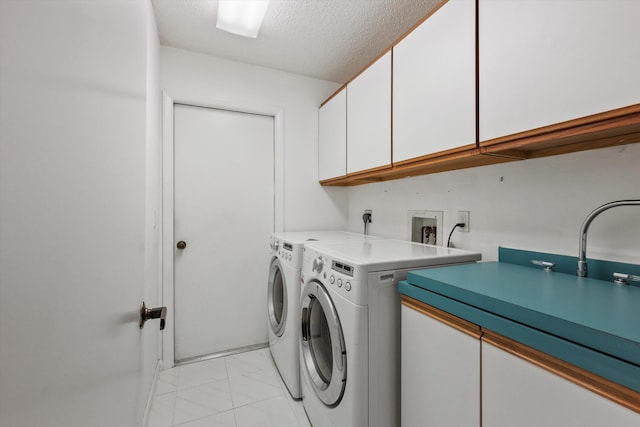 laundry area with washing machine and clothes dryer, cabinets, and a textured ceiling