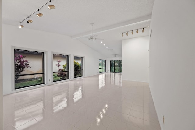 empty room with a textured ceiling, lofted ceiling with beams, ceiling fan, and light tile patterned flooring