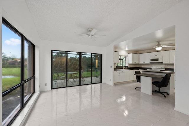 interior space with white cabinetry, sink, ceiling fan, vaulted ceiling, and white appliances