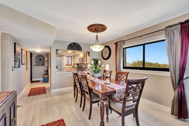 dining area with light wood-type flooring and a textured ceiling