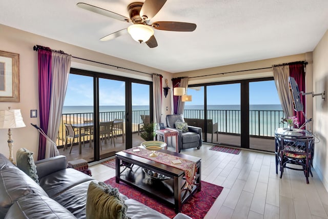 living room with ceiling fan, light hardwood / wood-style floors, and a water view