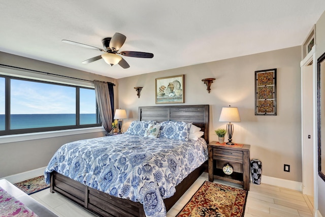 bedroom with ceiling fan and a water view