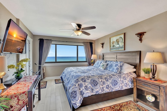 bedroom with a water view, light hardwood / wood-style flooring, and ceiling fan