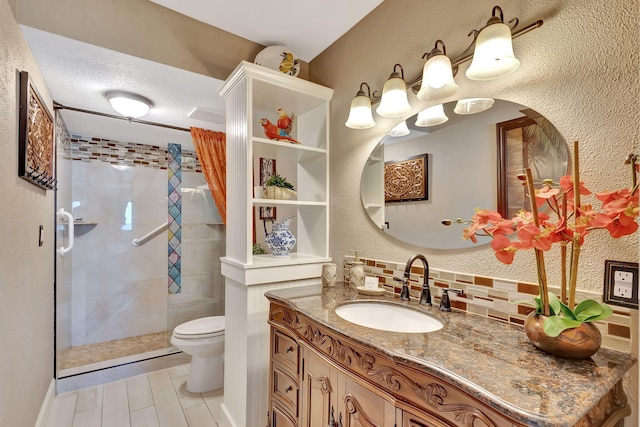 bathroom featuring a textured ceiling, toilet, decorative backsplash, a shower with door, and vanity