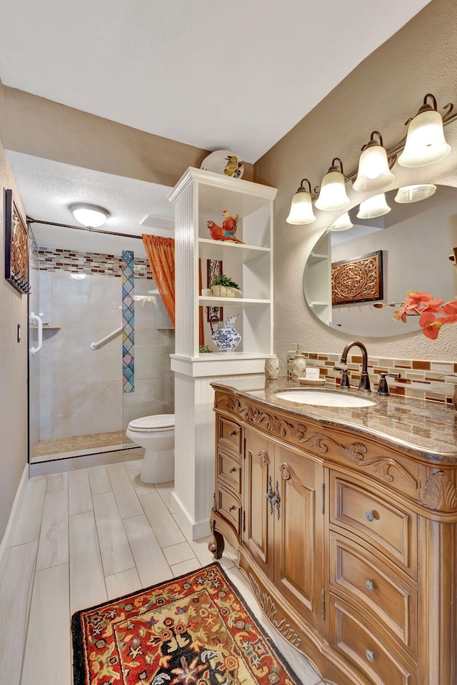 bathroom with toilet, vanity, and tiled shower