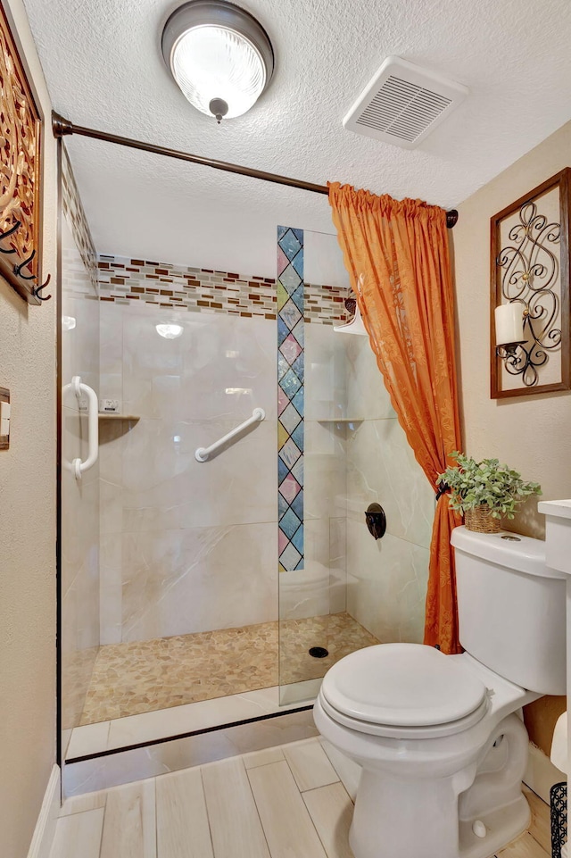 bathroom featuring a tile shower, a textured ceiling, and toilet