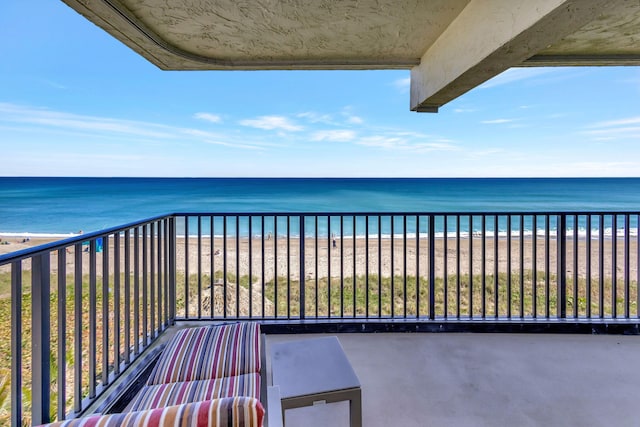 balcony featuring a view of the beach and a water view